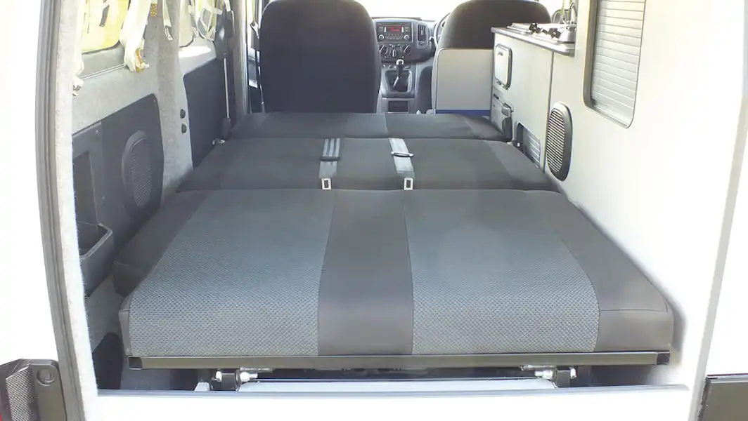 Seats folded down into a large double bed in the Small Campervan Nissan e-NV200 (Click to view full screen)
