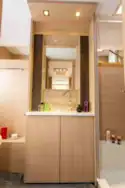 Slim shelved cabinets are on both sides of the mirror
