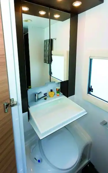 A substanttial washbasin findes down from within the mirrored cabinet (Click to view full screen)